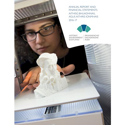 A photograph of a woman with glasses looking at a printed 3D model and the words "Annual Report and Financial Statements"