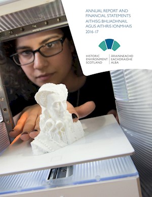 A photograph of a woman with glasses looking at a printed 3D model and the words "Annual Report and Financial Statements"