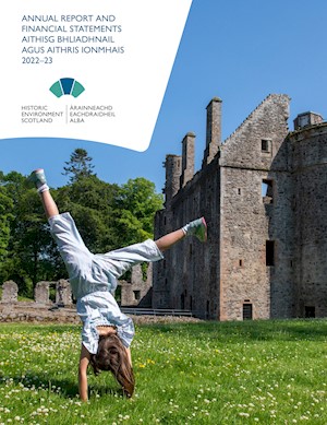 A child doing a handstand on grass with castle in the background